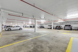 A multi-level parking garage with several cars parked, visible structural columns, and overhead lighting.