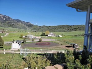 Surrounded by lush green fields and rolling hills, this serene property features a charming white building and a larger structure amidst a picturesque rural landscape.