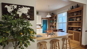 Una cocina con isla de madera, taburetes de bar, una lámpara colgante y un mapa mundial en la pared.