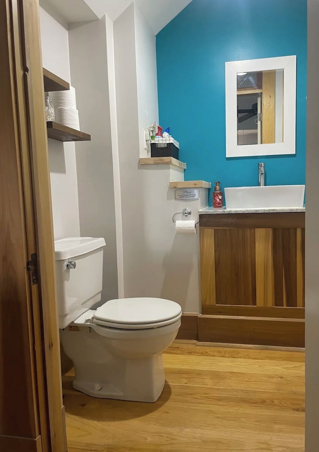 A bathroom with a white toilet, a wooden vanity with a sink, and a blue accent wall.