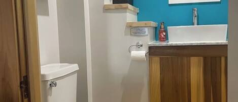 A bathroom with a white toilet, a wooden vanity with a sink, and a blue accent wall.