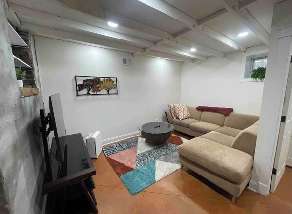 A living room with a sofa, a coffee table, a TV, and a fireplace.