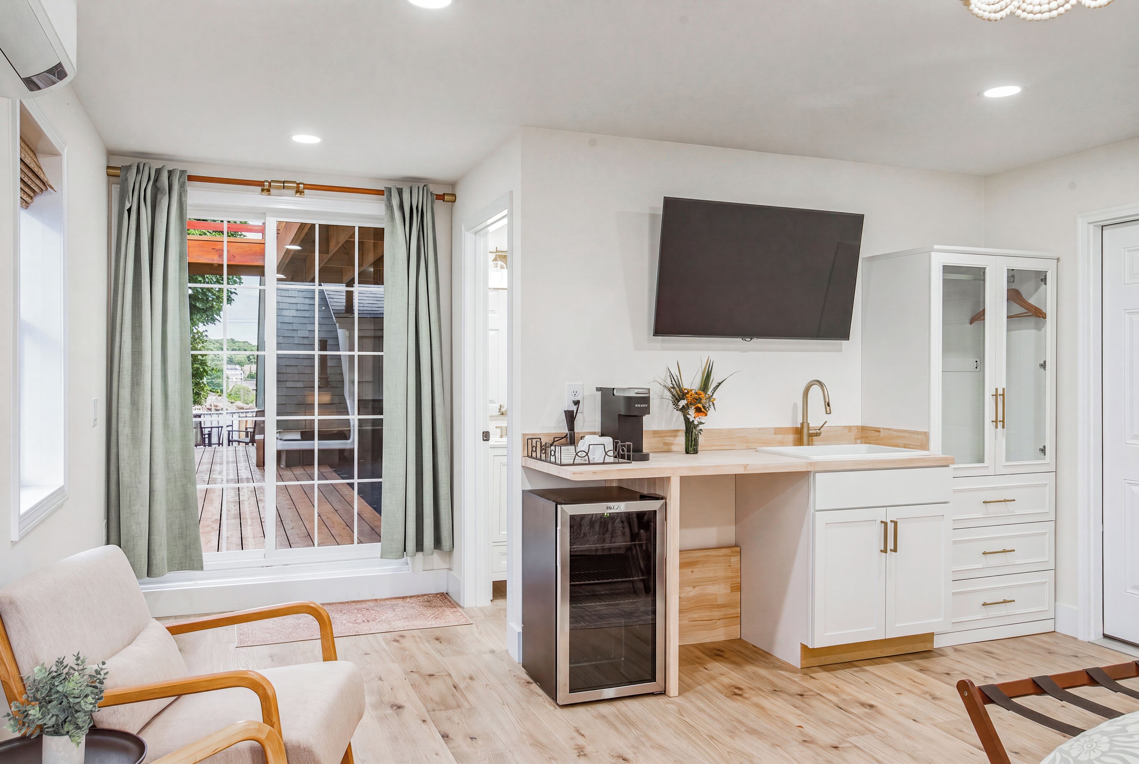 A modern kitchen with a built-in oven, a coffee machine, and a large window with curtains.