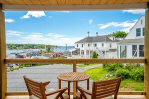 A wooden deck with a table and chairs, overlooking a marina with boats and houses.