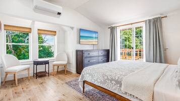 A bedroom with a bed, a desk, two chairs, a dresser, and a TV.