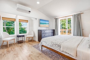 Un dormitorio con cama, escritorio, dos sillas, cómoda y televisor.