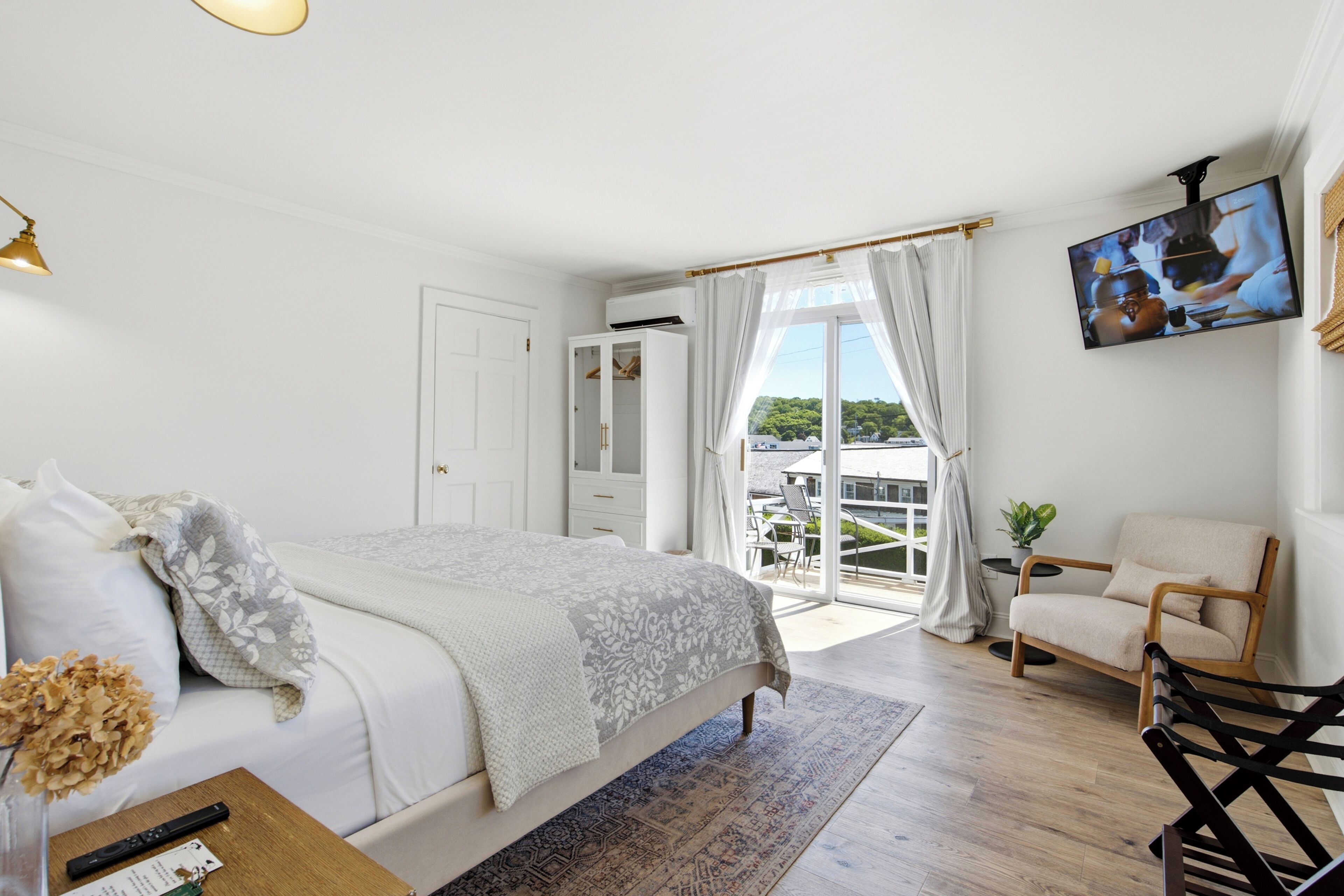Un dormitorio con cama, una silla, un televisor y vistas al exterior.