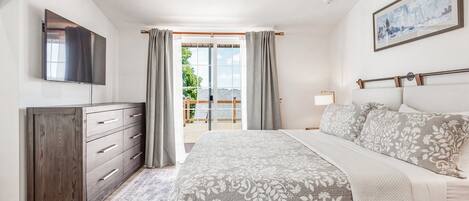 Un dormitorio con una cama, un aparador, un televisor y un cuadro en la pared.