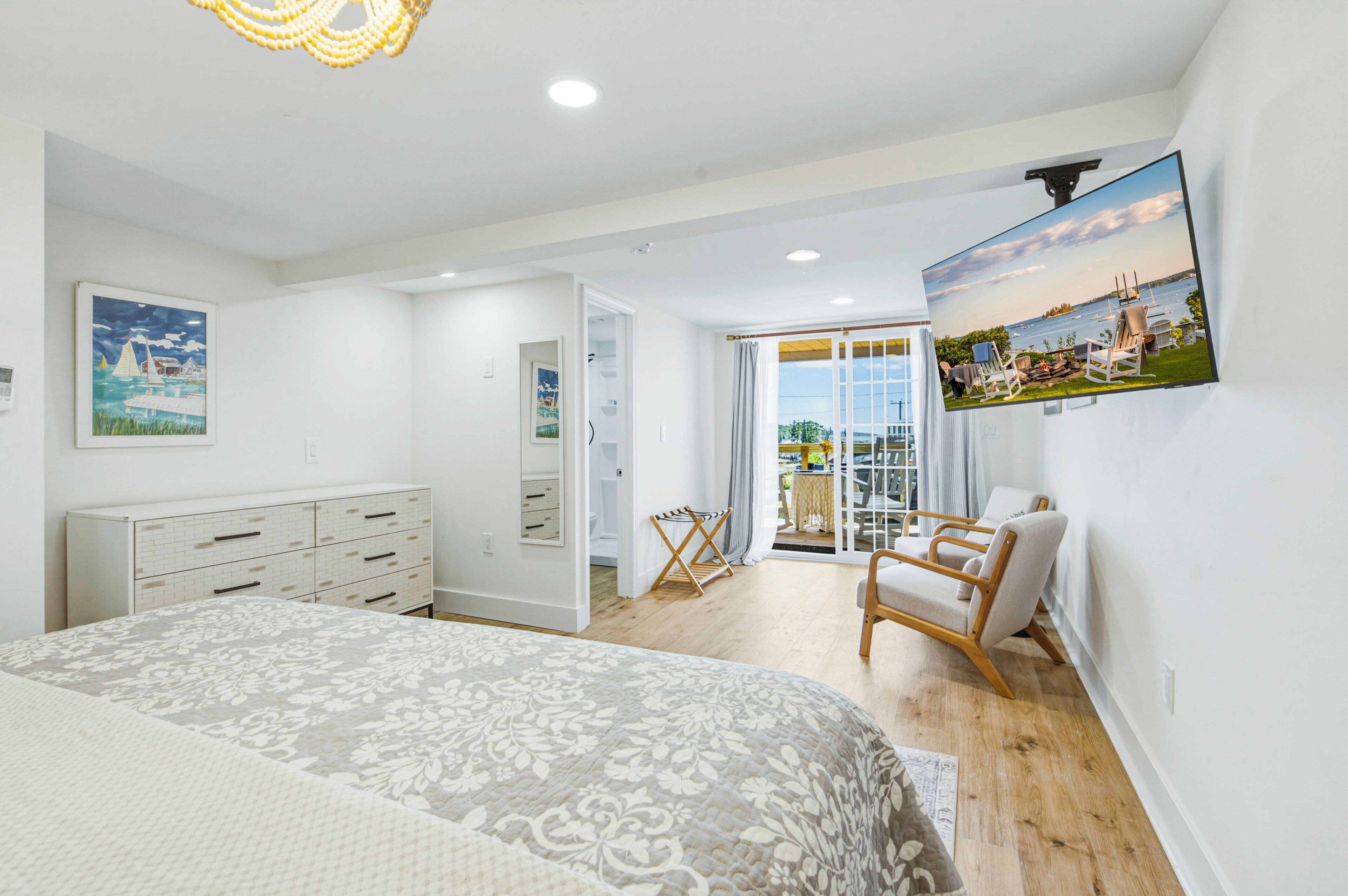 Un dormitorio con cama, cómoda y un ventanal con vistas al mar.