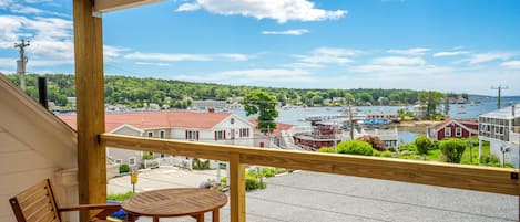 A wooden balcony with a view of a harbor, including boats and buildings.
