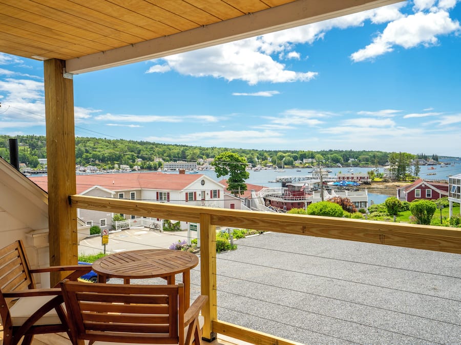 A wooden balcony with a view of a harbor, including boats and buildings.