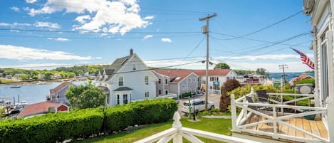 A coastal town with a white house, a dock, and a clear blue sky.
