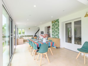 Un vaste espace dédié à la salle à manger, avec une longue table, des chaises de couleur turquoise et une nappe aux motifs éclatants.