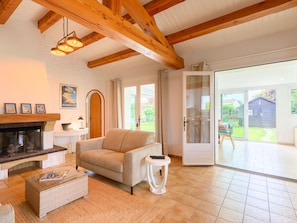 A living room with a fireplace, a sofa, a coffee table, and a view of the outside.