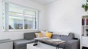 Een moderne woonkamer met een grijze bank, een witte salontafel en een boekenkast.