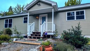 Ein zweistöckiges Haus mit Veranda, kleinem Garten und Kiesweg.