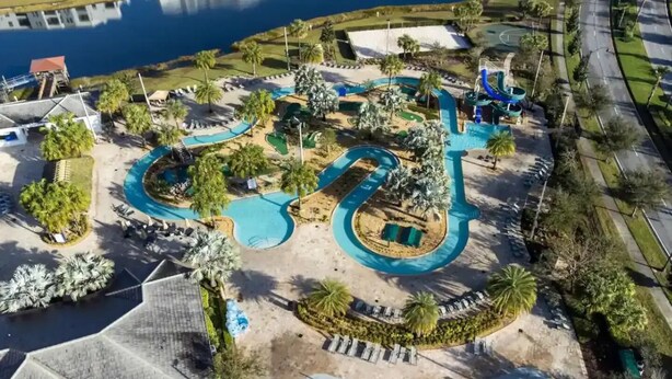 Une vue aérienne d’un parc aquatique avec de nombreux toboggans et des piscines, entouré de palmiers et bordé d’une étendue d’eau.