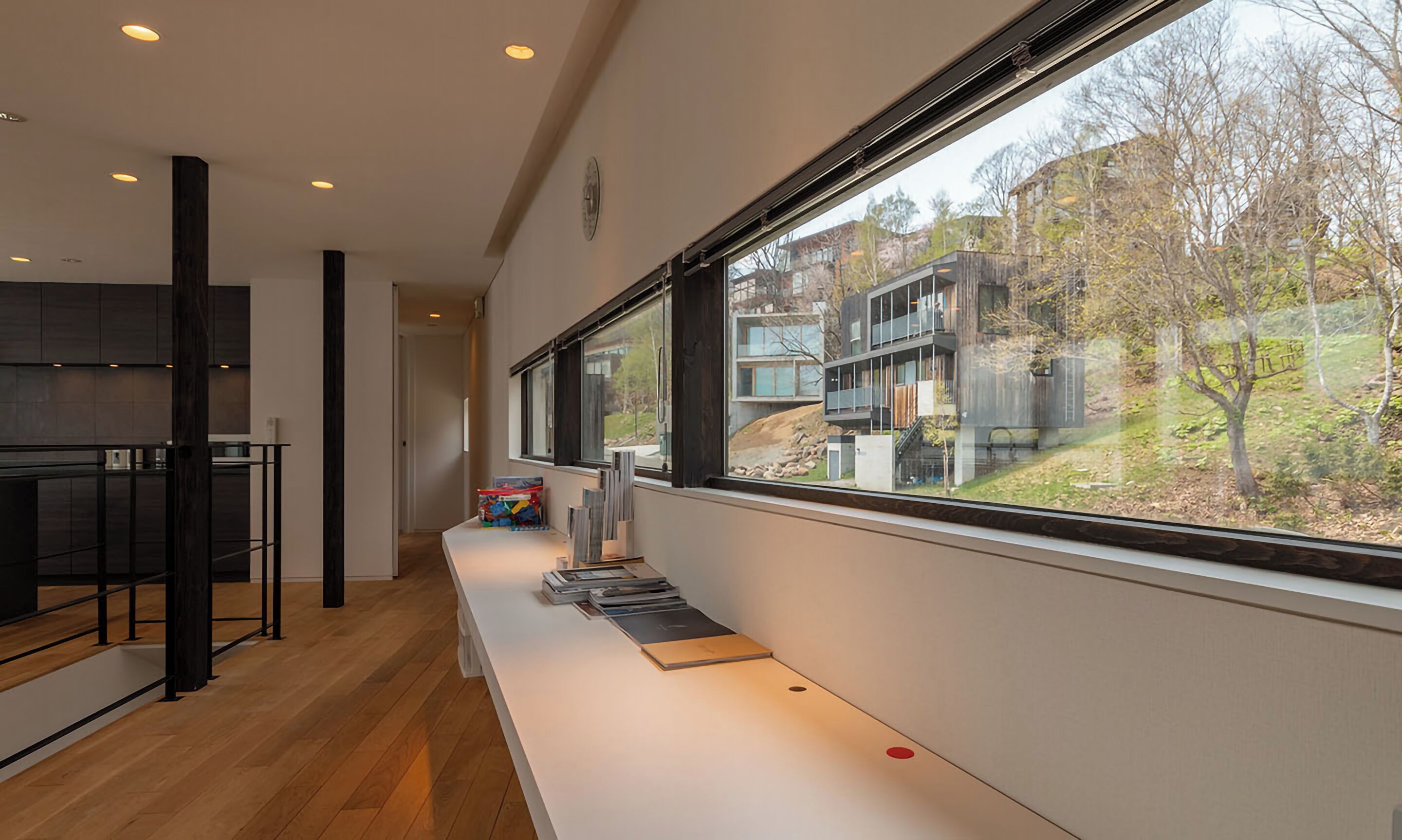 Una cucina moderna con un lungo bancone e vista su un edificio contemporaneo tramite ampie finestre.