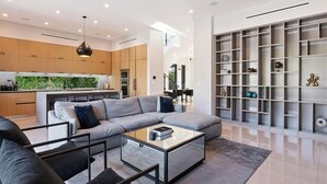 A modern living room with a grey sectional sofa, a glass coffee table, and a built-in bookshelf. - Chic 4-bedroom villa with WiFi, AC in vibrant Los Angeles (Los Angeles)