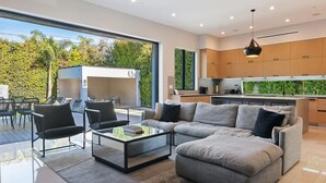 A modern living room with a sectional sofa, a glass coffee table, and a dining area with chairs. - Chic 4-bedroom villa with WiFi, AC in vibrant Los Angeles (Los Angeles)