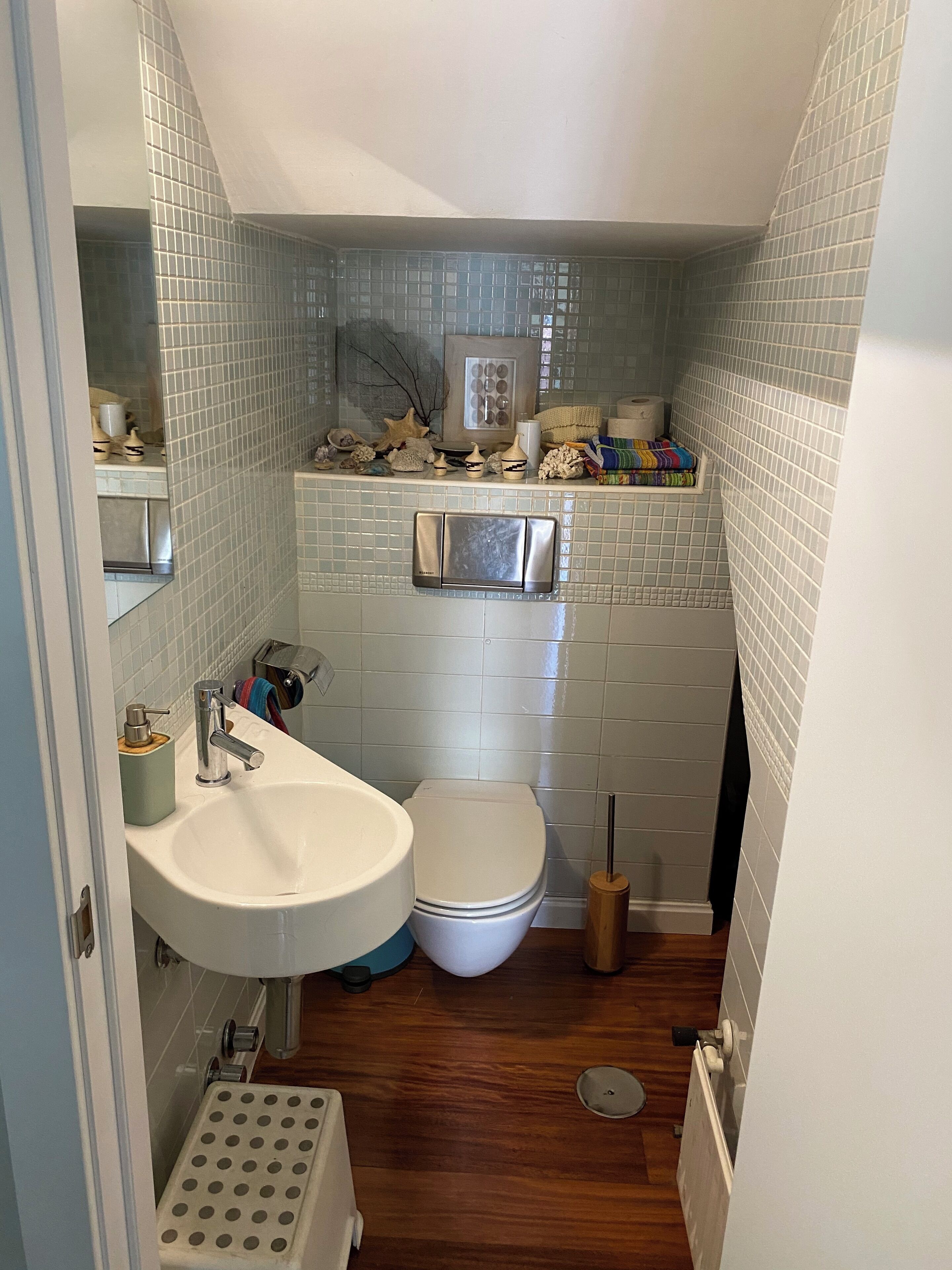 Un baño pequeño con un lavabo blanco, inodoro y un estante con artículos de tocador.