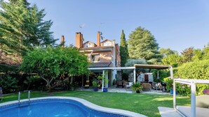 Ein Wohngrundstück mit Pool, überdachter Terrasse und einem Ziegelhaus mit Schornsteinen.