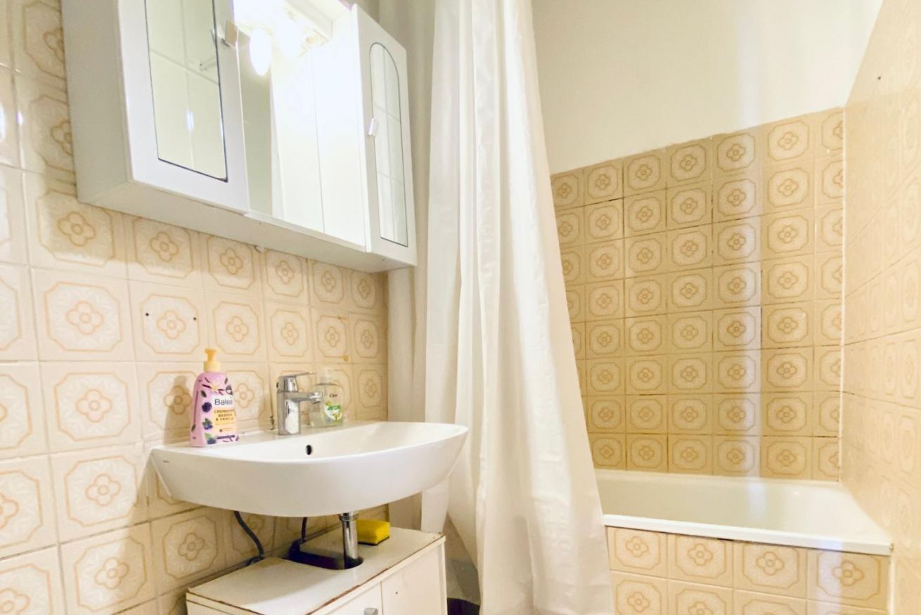 A bathroom with a white sink, a mirror, and a shower curtain.