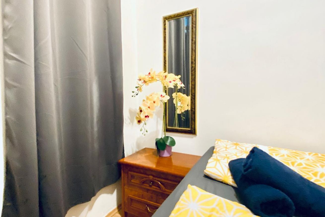 A bedroom with a bed, a dresser, a mirror, and a window with curtains.