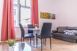 A modern living room with a dining table, two chairs, a sofa, and a window with curtains. - Very Spacious Central 5BR Apt, 10 Min to Augarten (Vienna)