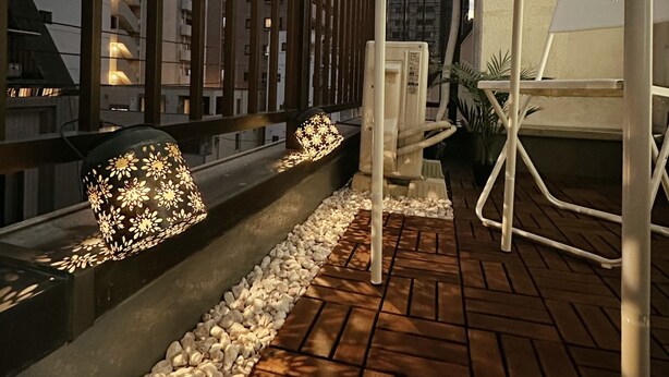 Una terraza en la azotea con zona de estar, una lámpara decorativa y vistas de edificios circundantes.