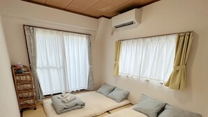 Habitación de hotel con dos camas, techo de madera, equipo de aire acondicionado y ventana con cortinas.