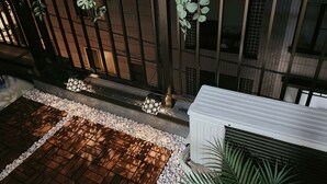 Un jardín interior moderno con suelo de madera, guijarros blancos y plantas colgantes.