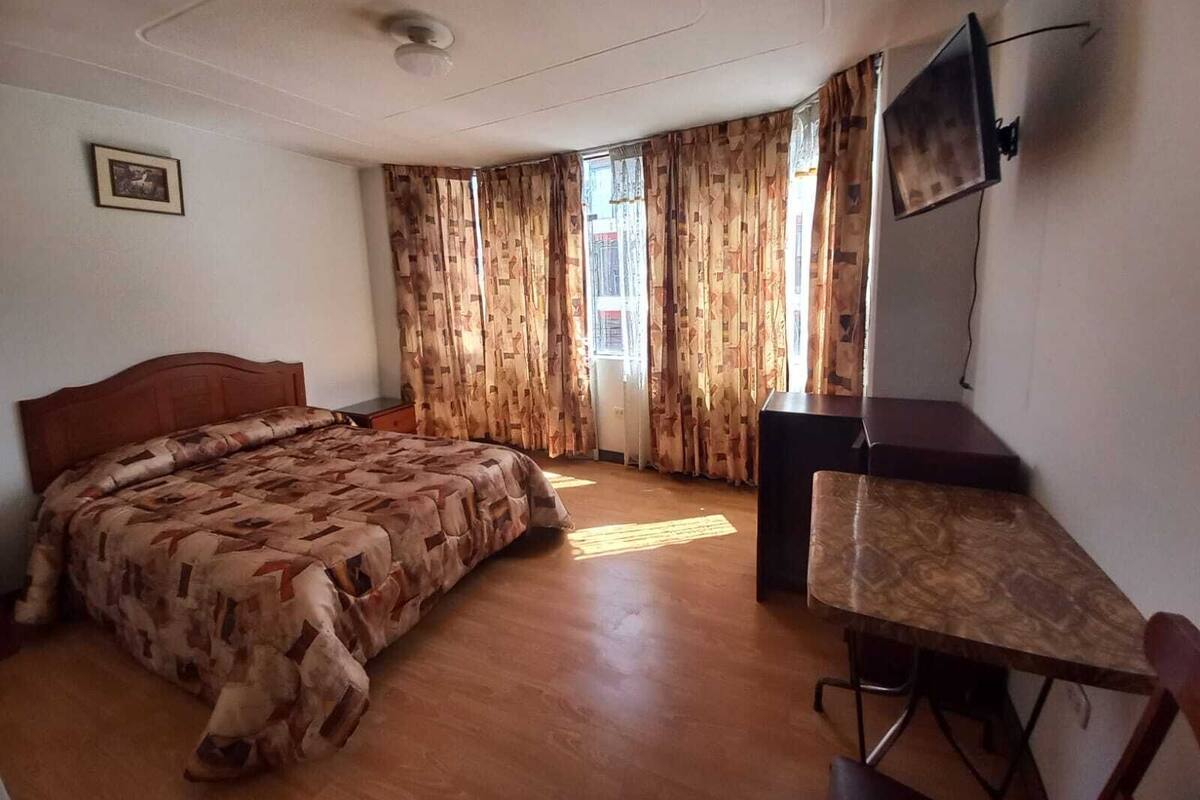 A bedroom with a bed, a desk, and a television.