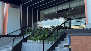 A modern building entrance with a staircase, glass railings, and potted plants. - Iloilo Grand Hotel (Iloilo)