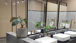 A modern bathroom with three white sinks, a large mirror, and potted plants. - Iloilo Grand Hotel (Iloilo)