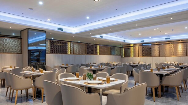 A modern dining area with multiple tables and chairs, featuring a contemporary design with geometric patterns on the walls and a clean, well-lit ambiance. - Iloilo Grand Hotel (Iloilo)