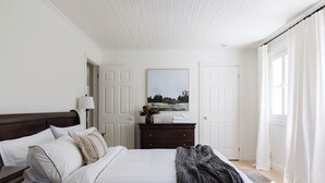 Een keurig opgemaakt slaapkamer met een bed, een dressoir en een schilderij aan de muur.