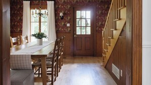 Een houten interieur met een eetgedeelte, een trap en een deur met bloemen behang.