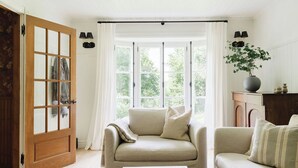 Een gezellige woonkamer met een beige bank, een witte salontafel en een houten deur met ruitpanelen.