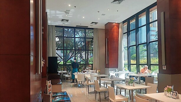 Un restaurante espacioso con amplios ventanales, muebles modernos y un ambiente limpio e iluminado.