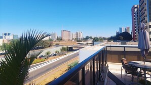 Un balcón con vistas a un paisaje urbano, que incluye edificios altos y una autopista.