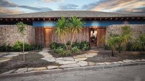 A modern house with a stone facade, a wooden front door, and a stone pathway leading to the entrance.