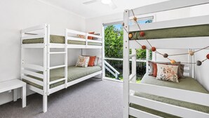 A room with bunk beds, a ceiling fan, and a view of greenery outside.