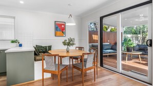 A modern kitchen with a dining area, a large window, and a sliding glass door leading to an outdoor seating area.