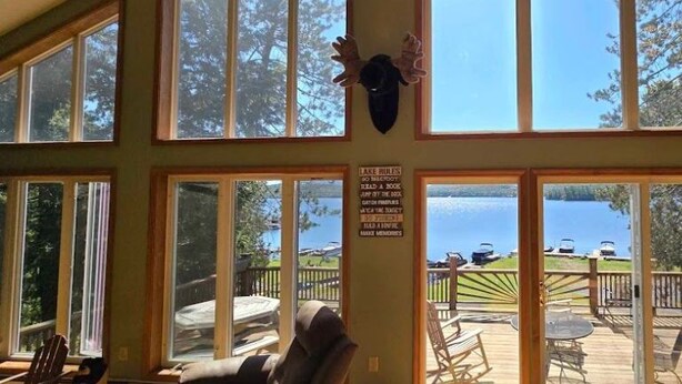 Et værelse med store vinduer med udsigt til en terrasse og en sø.