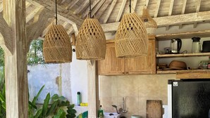 Une cuisine dotée d’un îlot central, de meubles en bois et de luminaires suspendus en osier.