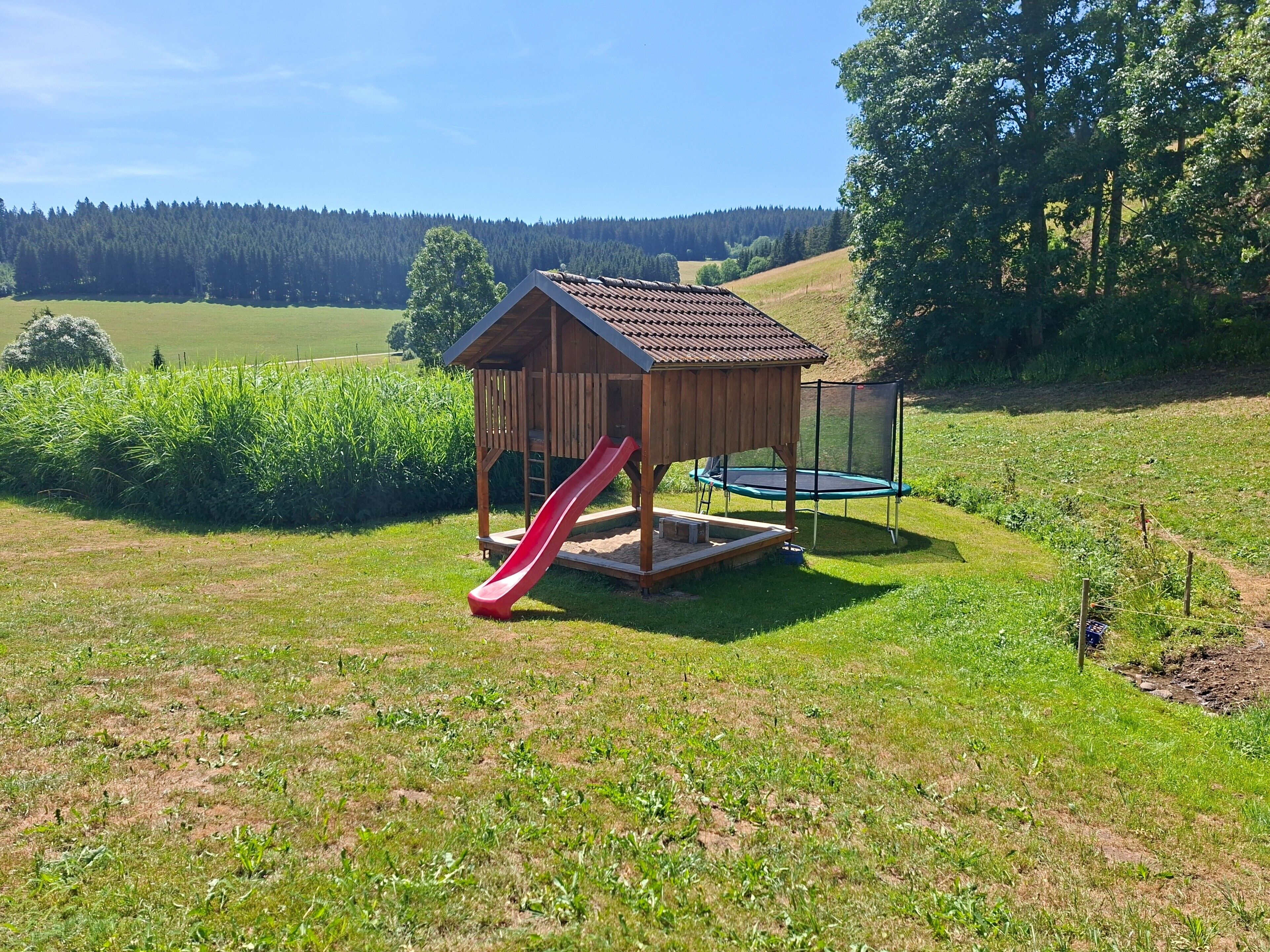 A playground with a slide and trampoline.