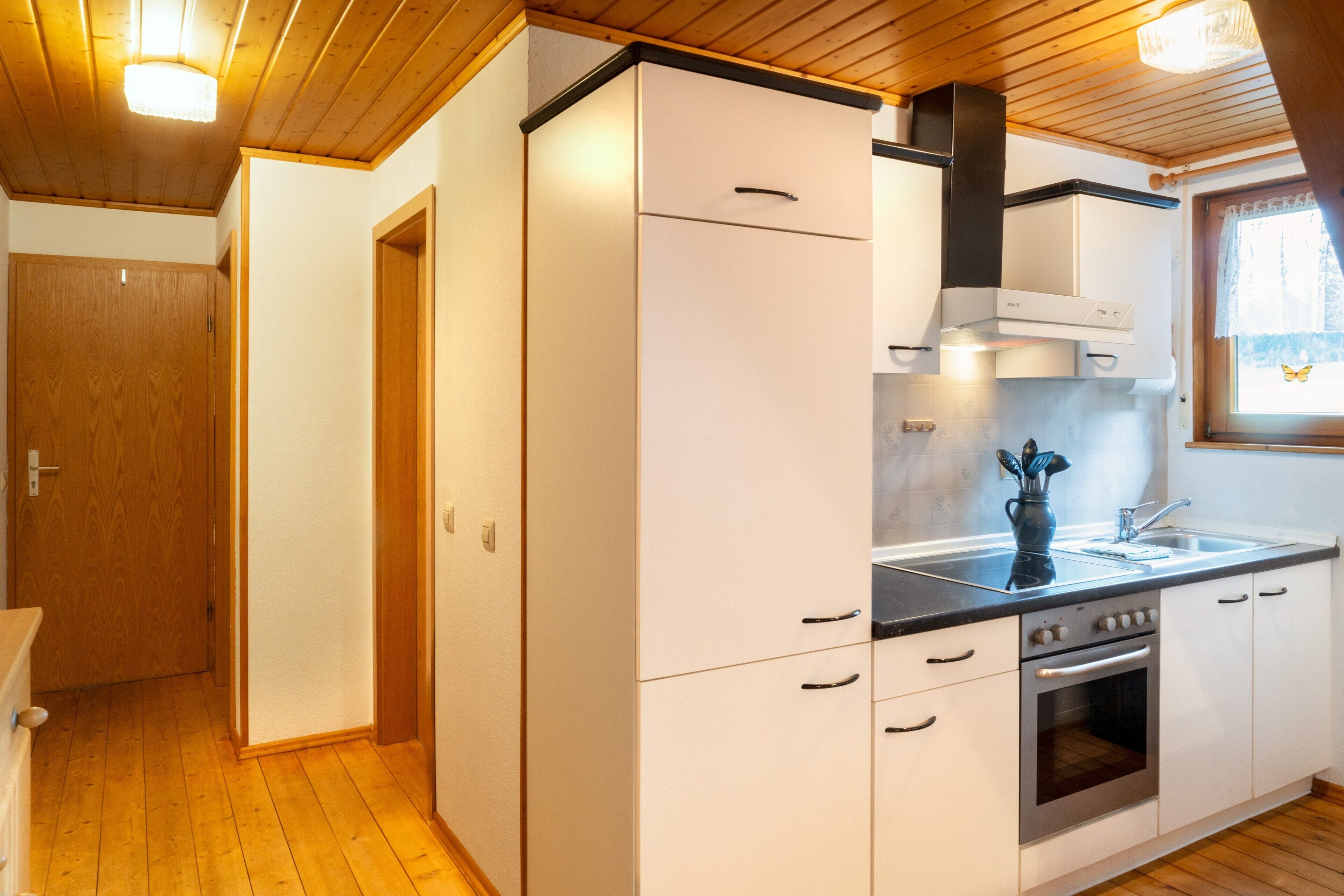 A compact kitchen with wooden cabinets, a stove, and a window with a butterfly sticker.