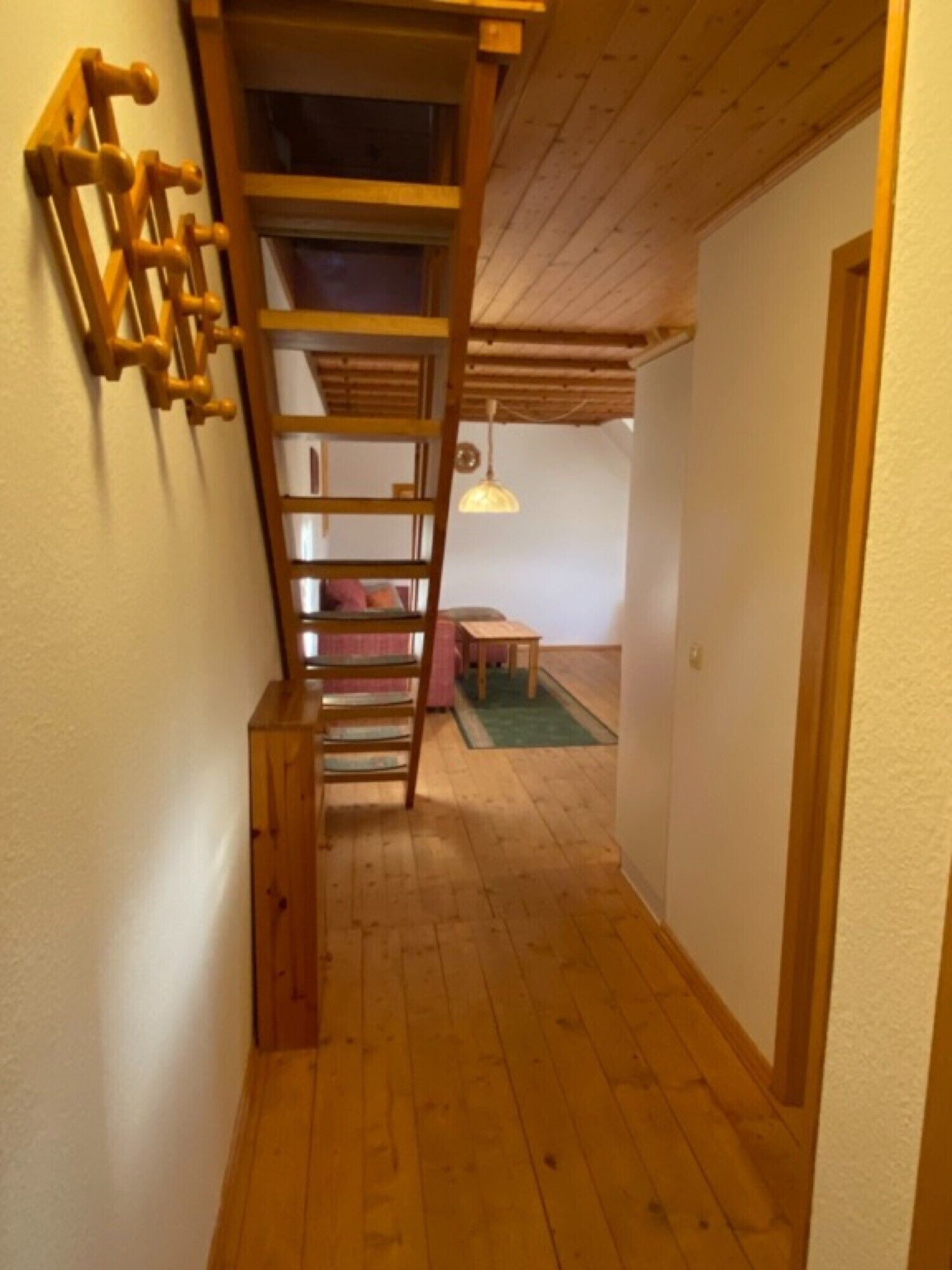 Een houten trap die leidt naar een hoger gelegen gedeelte met een bed en een tafel.