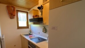 Eine kompakte Küche mit Holzausstattung, einem Backofen, einem Spülbecken und einem Fenster mit Vorhängen.